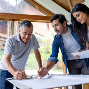 Latin American couple remodeling their house and taking to the architect while looking at blueprints